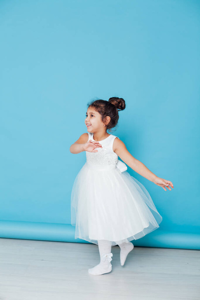 gyönyörű kislány fehér ruhában táncol a zenére - Fotó, kép