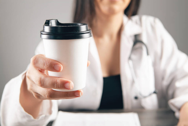 Doctor holding coffee in front of work table - Foto, immagini