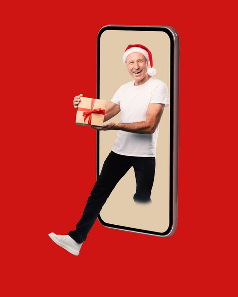 homem maduro dando presente de Natal saindo tela celular - Foto, Imagem