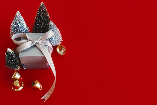 Joyeux Noël et bonne année ! Arbres de Noël et boîte cadeau sur fond rouge. Carte de vœux minimaliste moderne avec espace pour le texte. - Photo, image
