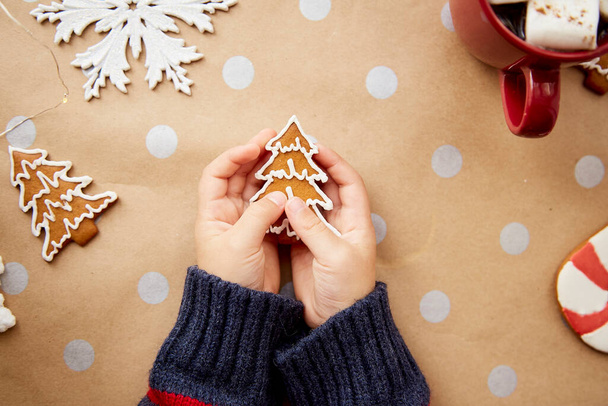 Christmas homemade christmas tree cookies in child hands among festive Christmas decorations with hot drink and marsmallows. Aesthetic Christmas atmosphere, home coziness and warmth concept - Photo, Image