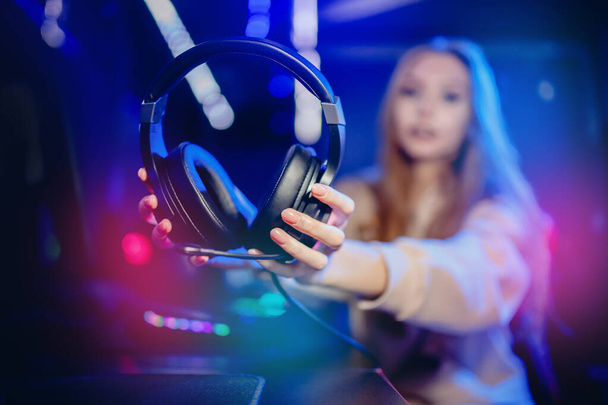 Kobieta trzymać słuchawki z mikrofonem do gier wideo i sportów cybernetycznych na neonowym tle - Zdjęcie, obraz