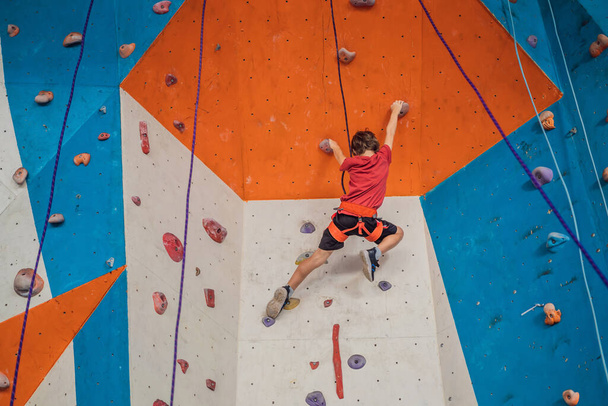 Boy at the climbing wall without a helmet, danger at the climbing wall - 写真・画像