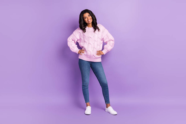 Photo of sweet charming dark skin woman wear pink sweater smiling arms waist isolated violet color background - Fotó, kép