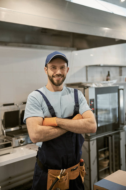 Vreugdevolle mannelijke werknemer staande in cafe keuken - Foto, afbeelding
