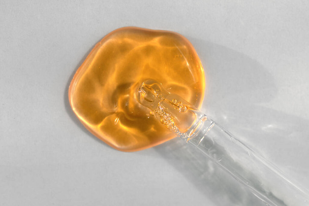 Піпетка з апельсиновою рідиною гіалуроновою кислотою на білому тлі. Концепція косметики та охорони здоров'я крупним планом
 - Фото, зображення