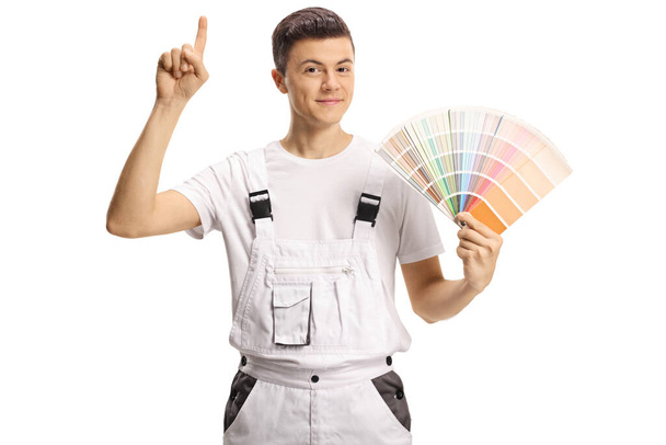 Young mail painter holding a color swatch palette and pointing up isolated on white background - Photo, image
