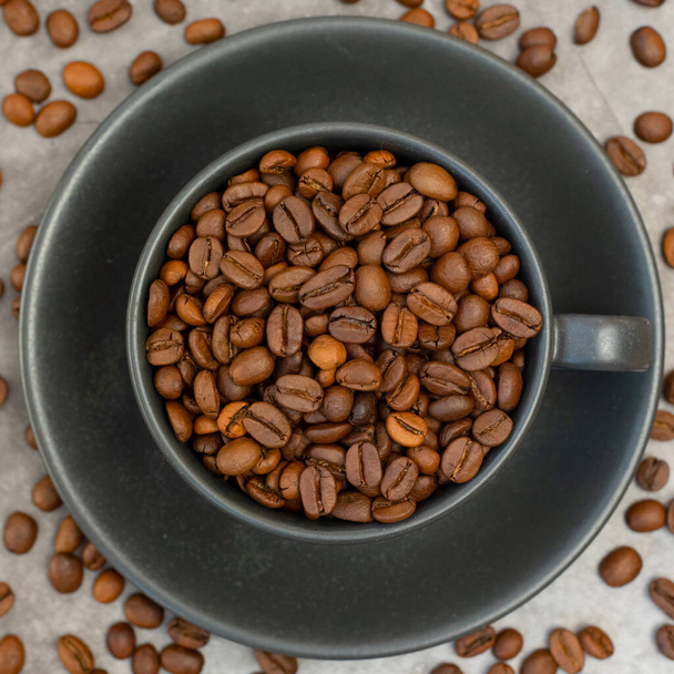 Kaffeetasse mit gerösteten Bohnen auf Steinhintergrund. Ansicht von oben. - Foto, Bild