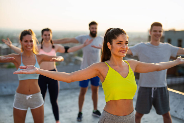 Group of happy fit people friends exercising together outdoor on rooftop. Sport, healthy life concept - Foto, afbeelding