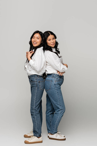 full length of happy asian mother and daughter in blue jeans and white shirts on grey - Фото, зображення