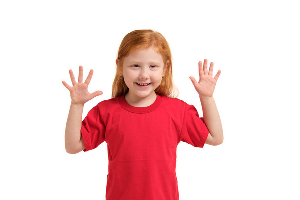 Το κοριτσάκι χαμογελάει με τα χέρια ψηλά. 5 ετών κορίτσι έκπληκτος με χαμόγελο και τα χέρια κοντά στα χέρια της - Φωτογραφία, εικόνα