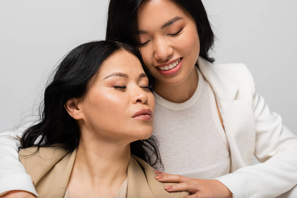 feliz asiático jovem filha abraçando mãe isolado no cinza - Foto, Imagem
