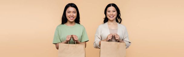 feliz asiático mãe e filha com compras sacos isolado no bege, banner - Foto, Imagem