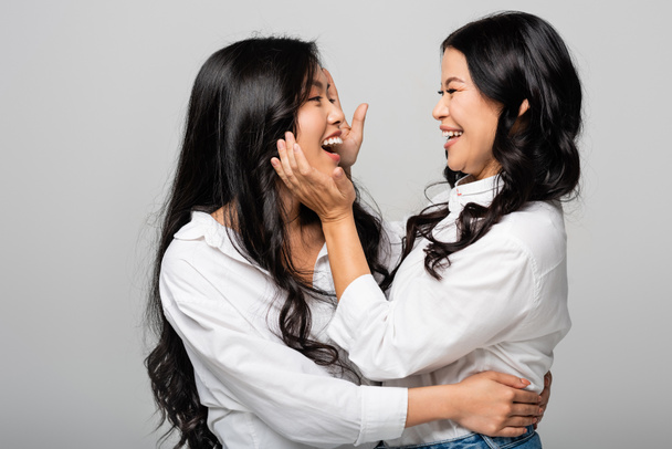 wesoła azjatycka matka i córka uśmiechające się do siebie odizolowane na szarości - Zdjęcie, obraz