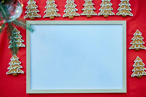 Kerst zelfgemaakte peperkoek koekjes met mock up frame. Feestelijke esthetische kaart op rode stof. Kerstsfeer. Vrolijk kerstfeest en gezelligheid thuis concept. Hoge kwaliteit foto - Foto, afbeelding