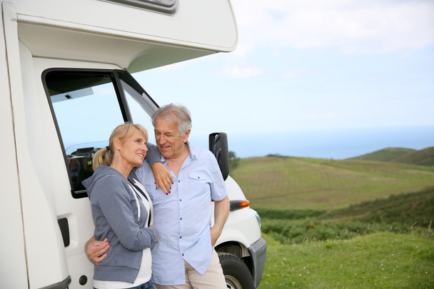 Couple standing by motorhome in countryside - Photo, Image