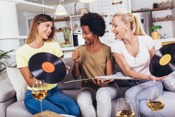 Happy young female friends at home listening vinyl at home. Choosing next record. - Foto, Bild