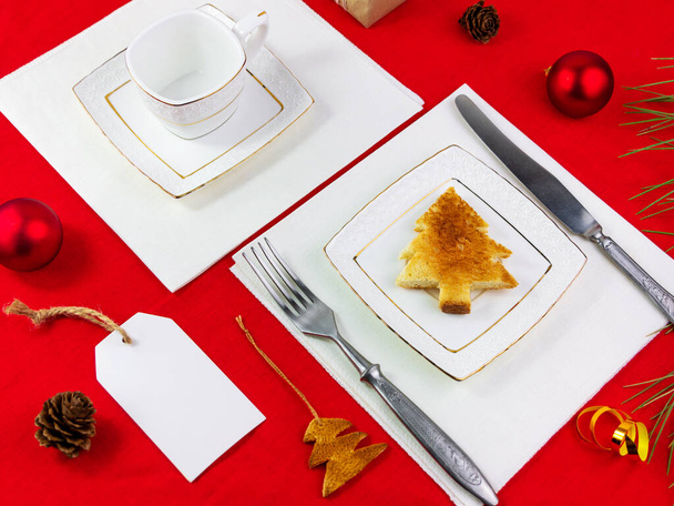 Christmas table setting toast on white plate silverware on red tablecloth background flat lay. New year festive party restaurant dinner decoration Winter Holiday Greeting card mockup invitation design - Photo, Image