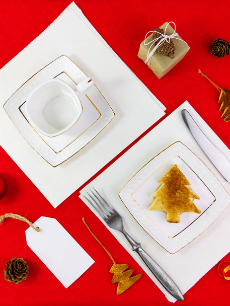Різдвяний стіл, що встановлює тости на білій тарілці, посуд на червоній скатертині, плоский. Новорічна святкова вечірка ресторан обід прикраси Зимові свята Вітальна листівка макет запрошення дизайну
 - Фото, зображення