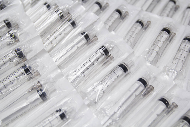 Medical syringes in a package. A bunch of unused, packaged syringes.Many new syringes lie strewn on a flat surface. - Foto, Bild