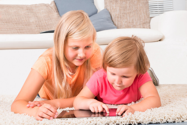 dzieci za pomocą tabletu, leżąc na dywanie - Zdjęcie, obraz