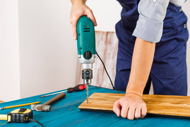 Handyman in blue uniform works with electricity automatic screwdriver. House renovation conception. - Zdjęcie, obraz