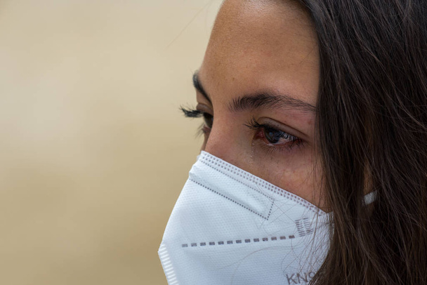 BARCELON, SPAIN - Nov 29, 2021: Sad woman in protective face mask with tears eyes during serious illness. Barcelona, Spain, November 29th 2021. - Foto, afbeelding