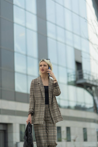 Επιχειρηματίας περπατά και μιλάει στο τηλέφωνο με τους συνεργάτες της - Φωτογραφία, εικόνα