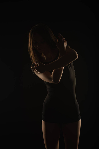 Perfect female silhouette posing with her arms on black background - Valokuva, kuva