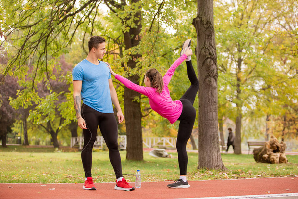 Attractive and fit girl is stretching her leg while holding her boyfriend - Valokuva, kuva