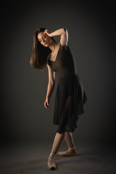 Elegant and beautiful ballerina is fixing her hair while thinking of the next ballet pose - 写真・画像
