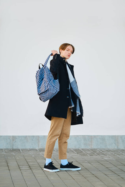 Full length portrait of young student with backpack in old wool coat, scarf and short trousers outdoor - Foto, imagen
