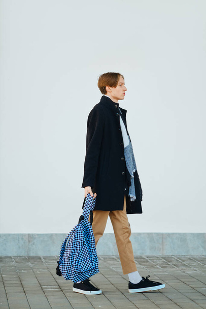 Full length portrait of young student walks with backpack in old wool coat, scarf and short trousers outdoor - Foto, imagen