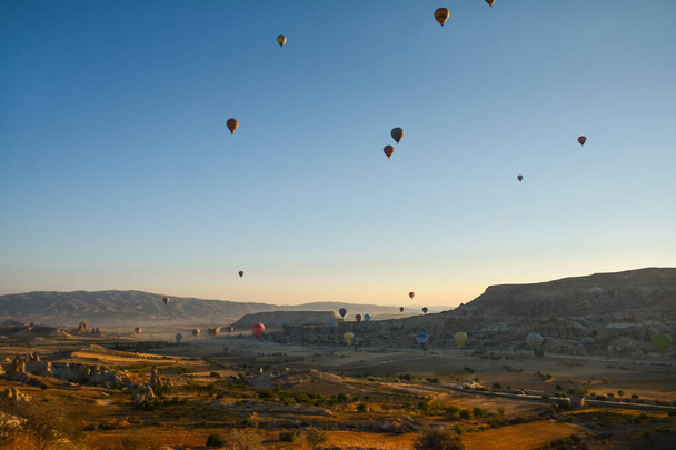 Amazing balloons soaring at sunrise among the bizarre mountains of Cappadocia - Foto, afbeelding