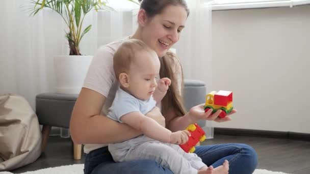 Little baby boy having fun with mother and playing in toy cars on floor. Concept of family having time together and children development - Footage, Video