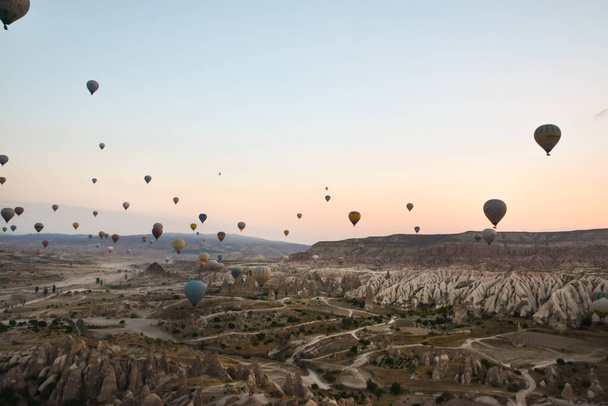 Amazing balloons soaring at sunrise among the bizarre mountains of Cappadocia - Фото, изображение