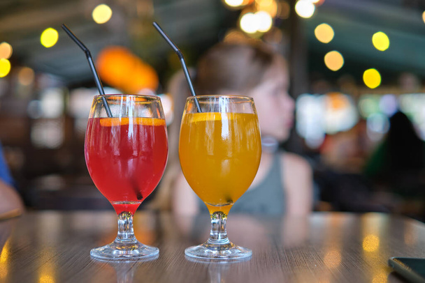 Dois copos com bebida doce saborosa amarela e vermelha na mesa do restaurante. - Foto, Imagem