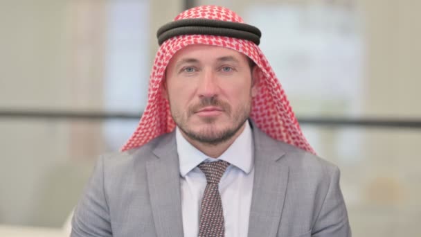 Portret poważnego arabskiego biznesmena w średnim wieku patrzącego w kamerę  - Materiał filmowy, wideo