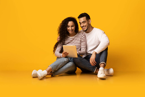 Cheerful Young Arab Couple Browsing Internet On Digital Tablet In Studio - Foto, Imagem