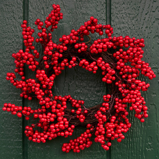 A holiday decorative winterberry wreath on a green barn door - Photo, Image
