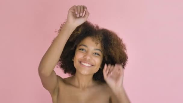 Joven bonita mujer de piel oscura bailando vigorosamente sobre fondo rosa de cerca - Metraje, vídeo