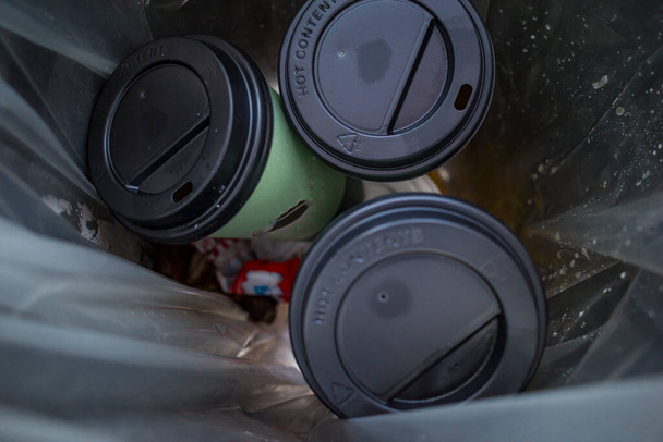Drie afhaalkopjes koffie in een vuilnisbak. - Foto, afbeelding