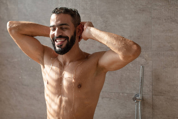 przystojny młody arabski mężczyzna model cieszy biorąc gorący prysznic - Zdjęcie, obraz