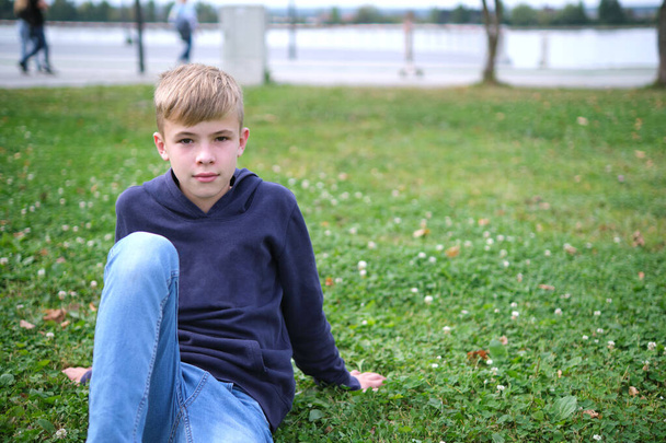 Portrait of child boy outdoors resting on grass lawn. - Photo, image