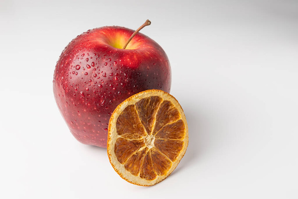 maçã vermelha e uma fatia de laranja seca em um fundo branco - Foto, Imagem