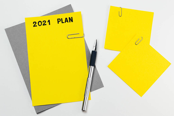 Żółty arkusz na szarej tabletce z ręcznie napisanym planem na 2021 r. Notatki do ustawiania bramki. Używane kombinacje kolorów trendu 2021 żółty i szary - Zdjęcie, obraz