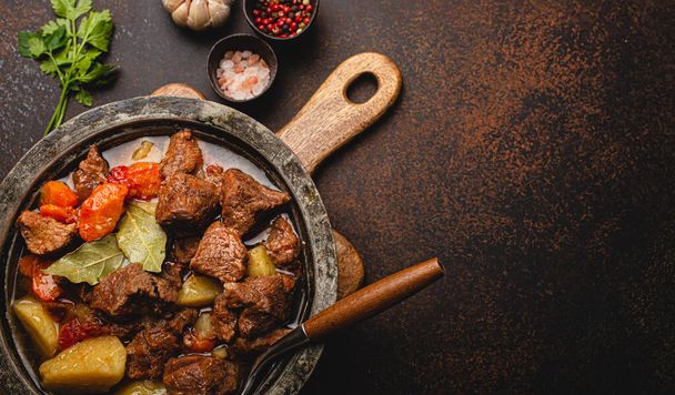 Meat beef stew with vegetables and gravy in rustic metal pot top view copy space - Foto, Imagem