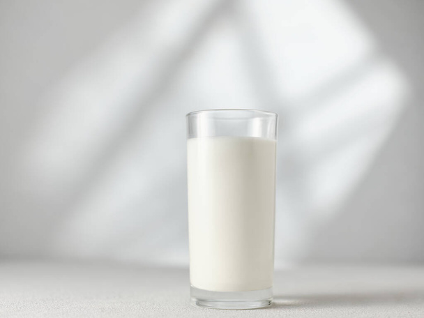 Glass of milk on the table with morning light from the window - Fotó, kép