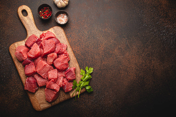Mięso wołowe surowe kostki do gulaszu na drewnianej desce do krojenia - Zdjęcie, obraz