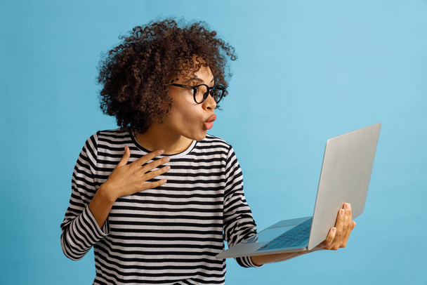 Шокированная молодая женщина использует ноутбук в студии - Фото, изображение